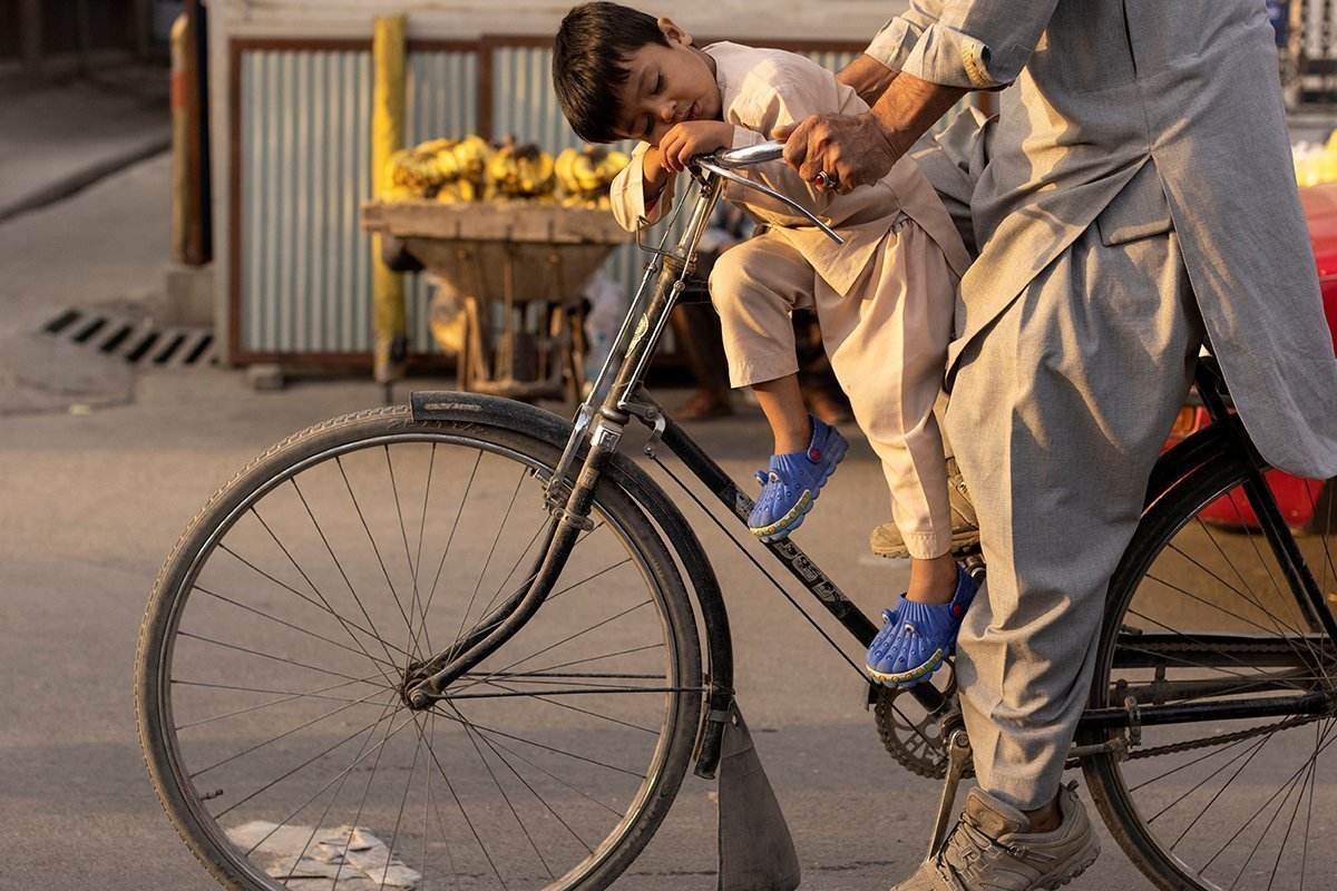 A Boy Sleeps As He Rides A Bicycle In Kabul
