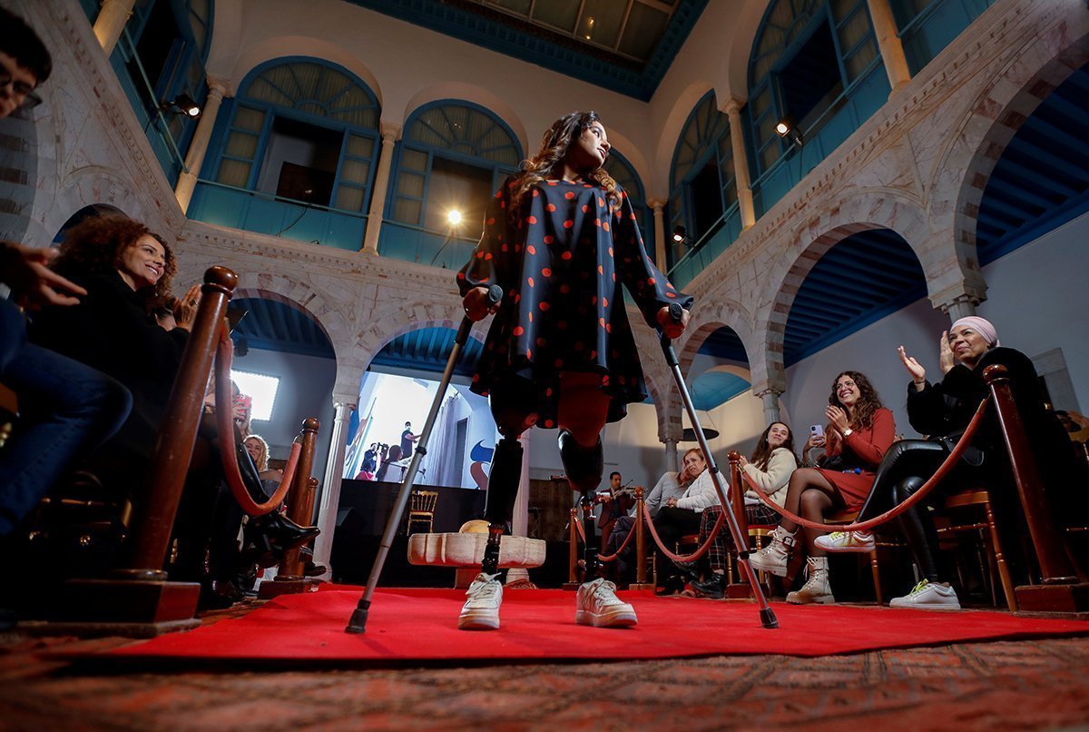 A Woman With Prosthetic Legs Walks On Crutches During A Fashion Show In Sidi Bou Said