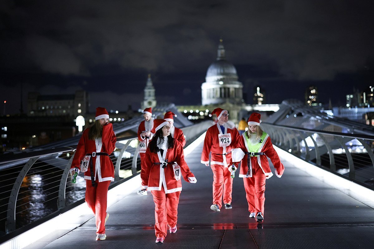 People Dressed As Santa Claus Walk Over Millennium Bridge Before Taking Part In A Fun Run On The South Bank In London