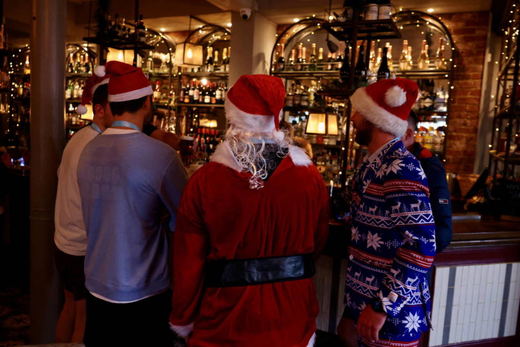 People Dressed In Christmas Outfits Stand At A Bar