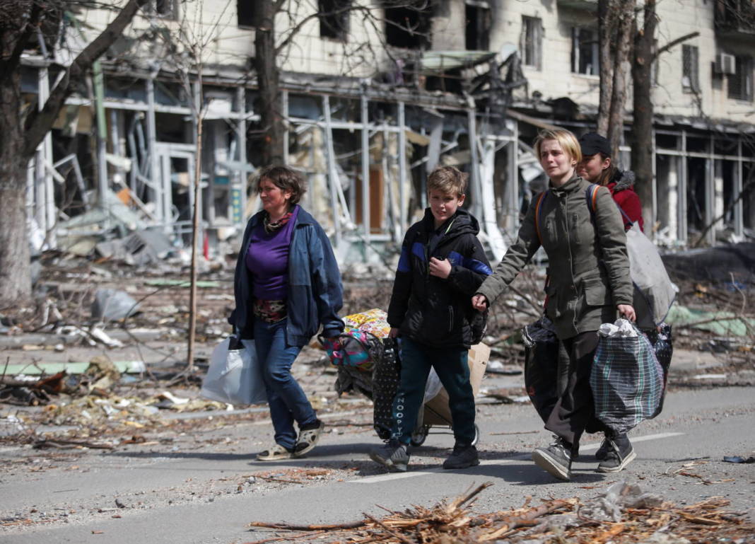 Residents Carry Their Belongings Along A Street Near A Building Burnt In The Course Of The Ukraine Russia Conflict, In Mariupol