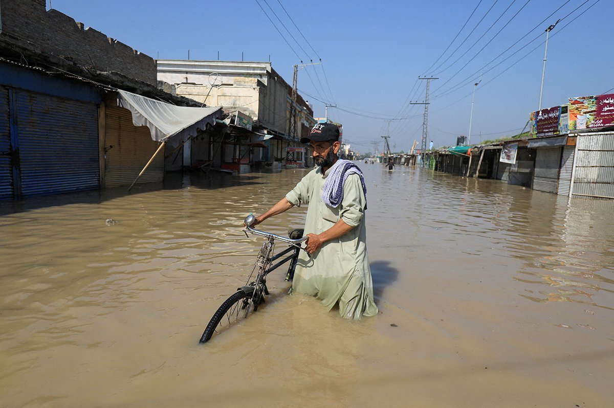 A Man Walks With A Bicycle In Flood Water Following Rains And Floods During The Monsoon Season In Nowshera