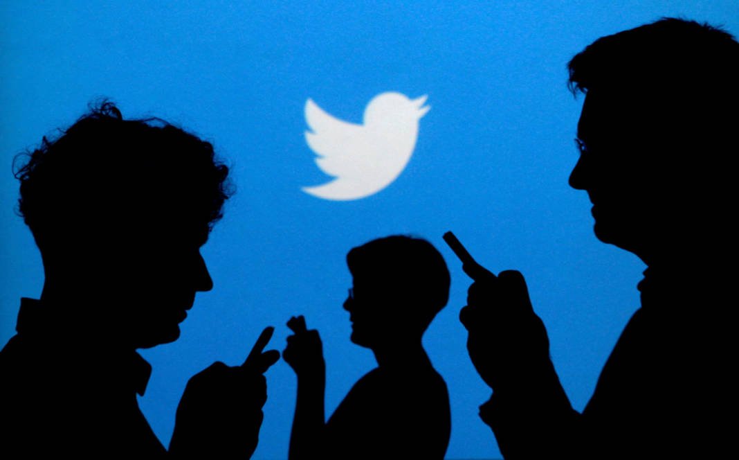 File Photo: File Photo: People Holding Mobile Phones Are Silhouetted Against A Backdrop Projected With The Twitter Logo