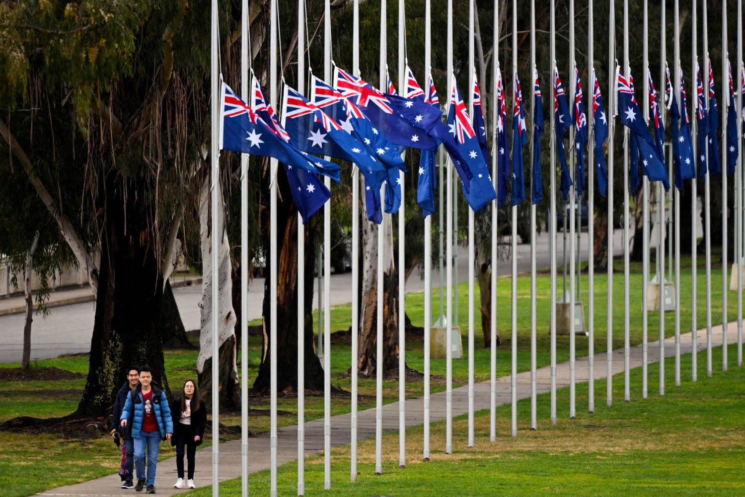 Visitors Walk Past Australian Flags Flying At Half Mast Outside Parliament House In Canberra