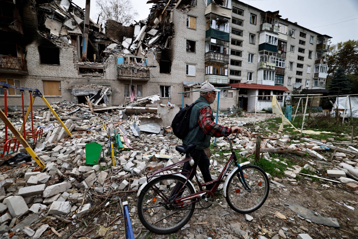 A Man Walks With His Bicycle Past A Destroyed Building, Amid Russia's Attack On Ukraine, In The Newly Recaptured Town Of Sviatohirsk