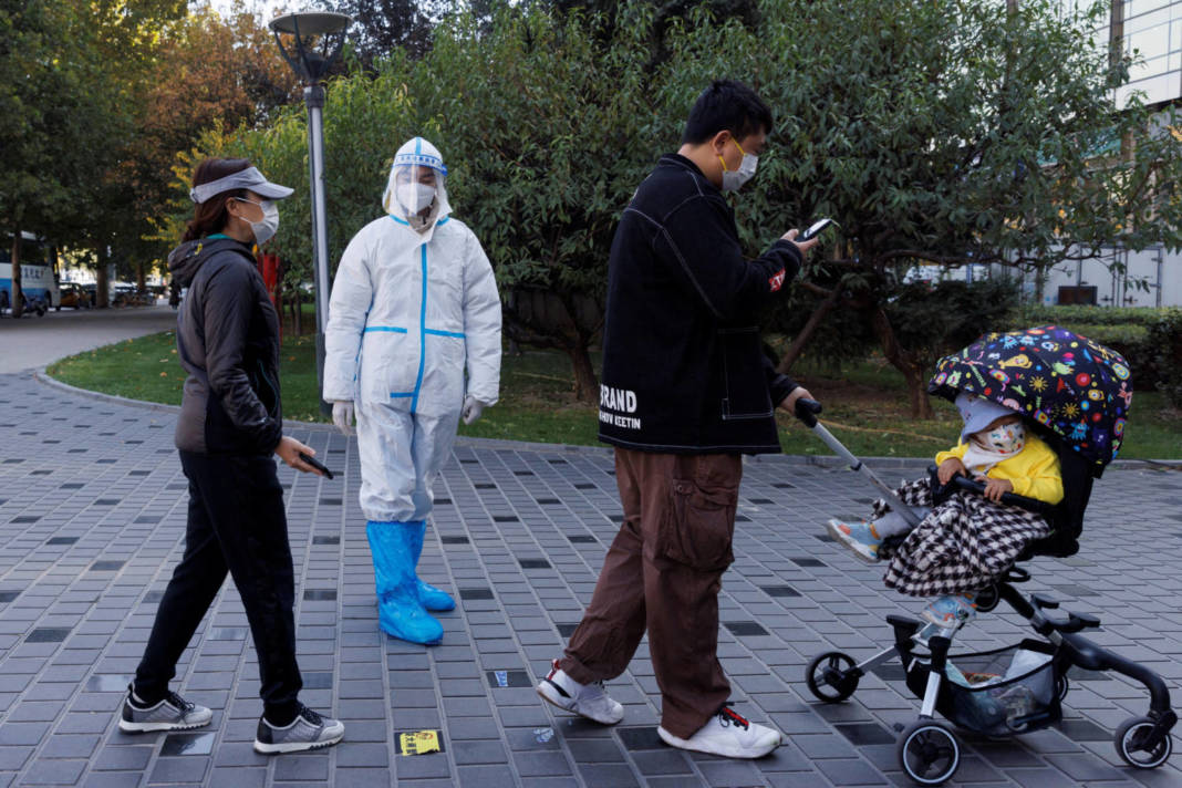 File Photo: A Pandemic Prevention Worker Wears A Protective Suit As People Line Up To Get Swab Tests At A Testing Booth As Outbreaks Of Coronavirus Disease (covid 19) Continue In Beijing