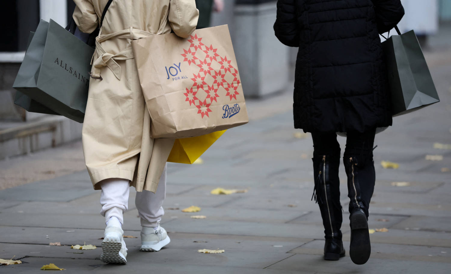 People Carry Shopping Bags As They Walk Along A Street In Manchester