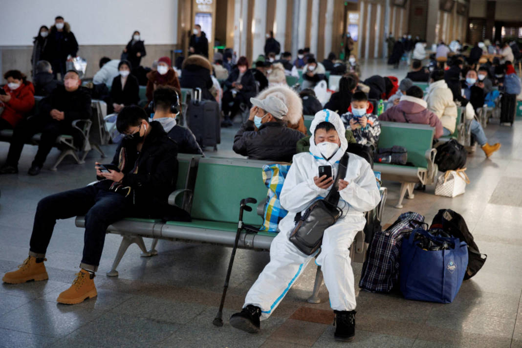 File Photo: A Person Wearing A Protective Suit Sits In Beijing Railway Station As Passengers Wait To Board A Train To Travel For Spring Festival Ahead Of Chinese Lunar New Year Festivities In Beijing
