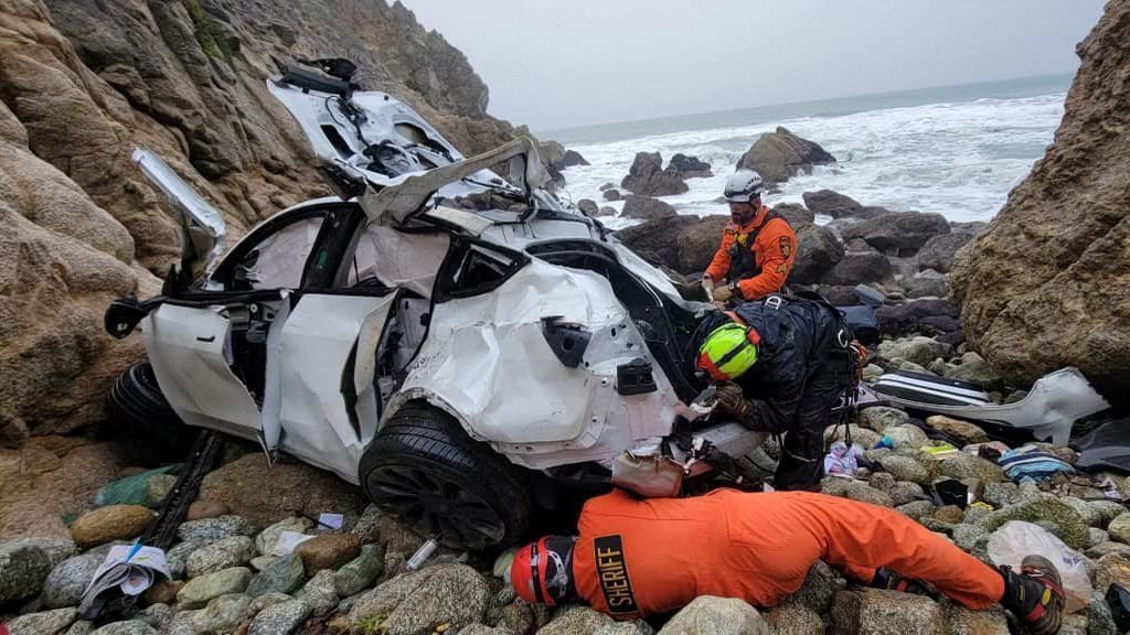 Rescuers Work On Retrieving A Destroyed Tesla Sedan That Had Plunged Off A Cliff In California
