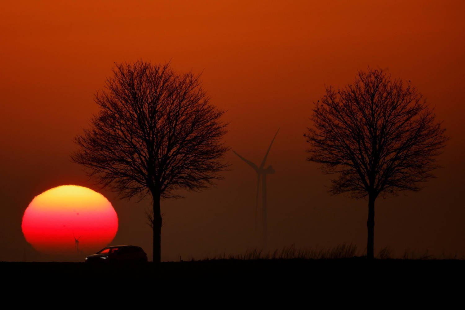 A Car Drives In Front Of Power Generating Windmill Turbines On The Cambrai Arras Road During Sunset In Epinoy