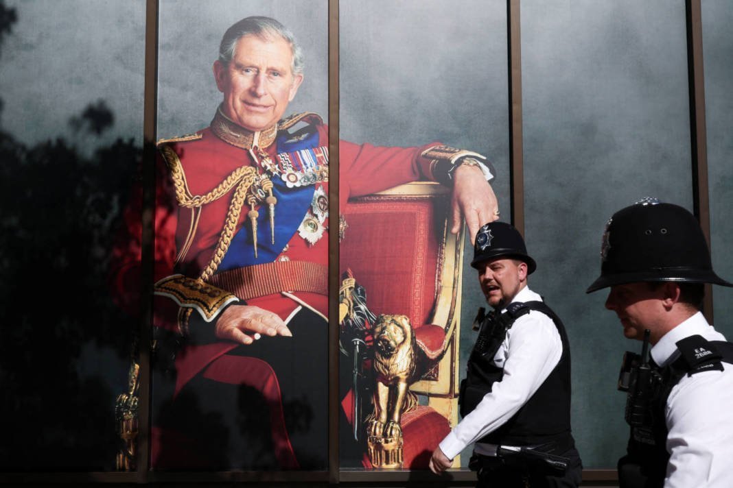 Police Officers Walk Past Britain's King Charles' Picture, A Day After Britain's King Charles And Queen Camilla's Coronation Ceremony, In London