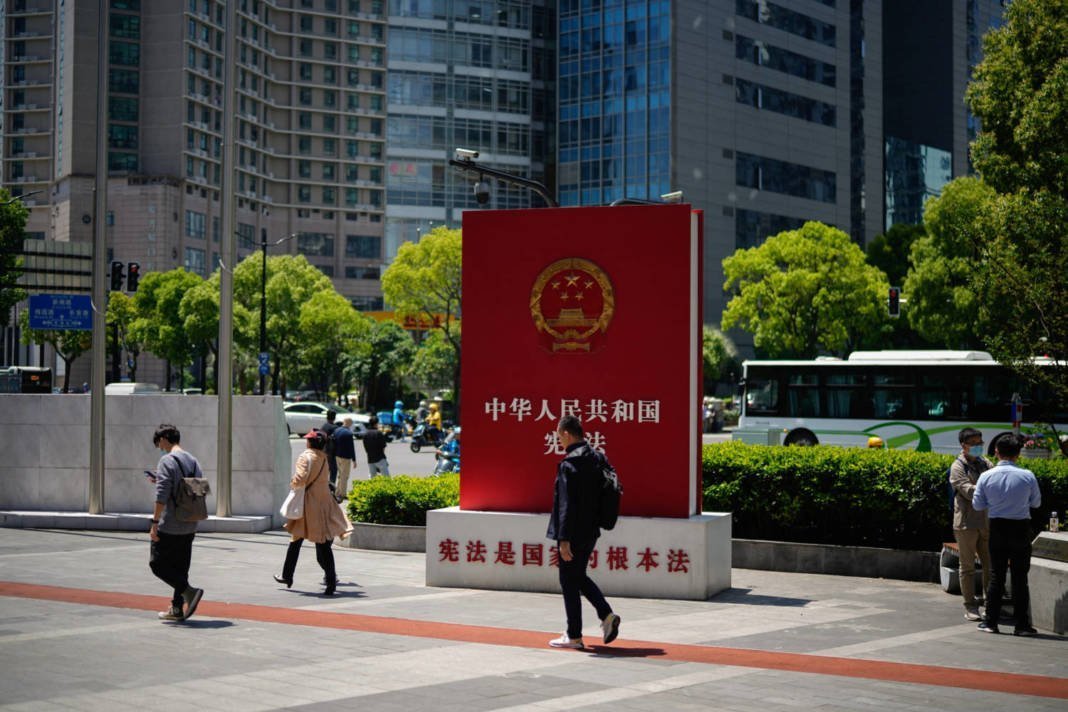 People Walk Past A Sign Promoting The Chinese Constitution On A Street In Shanghai