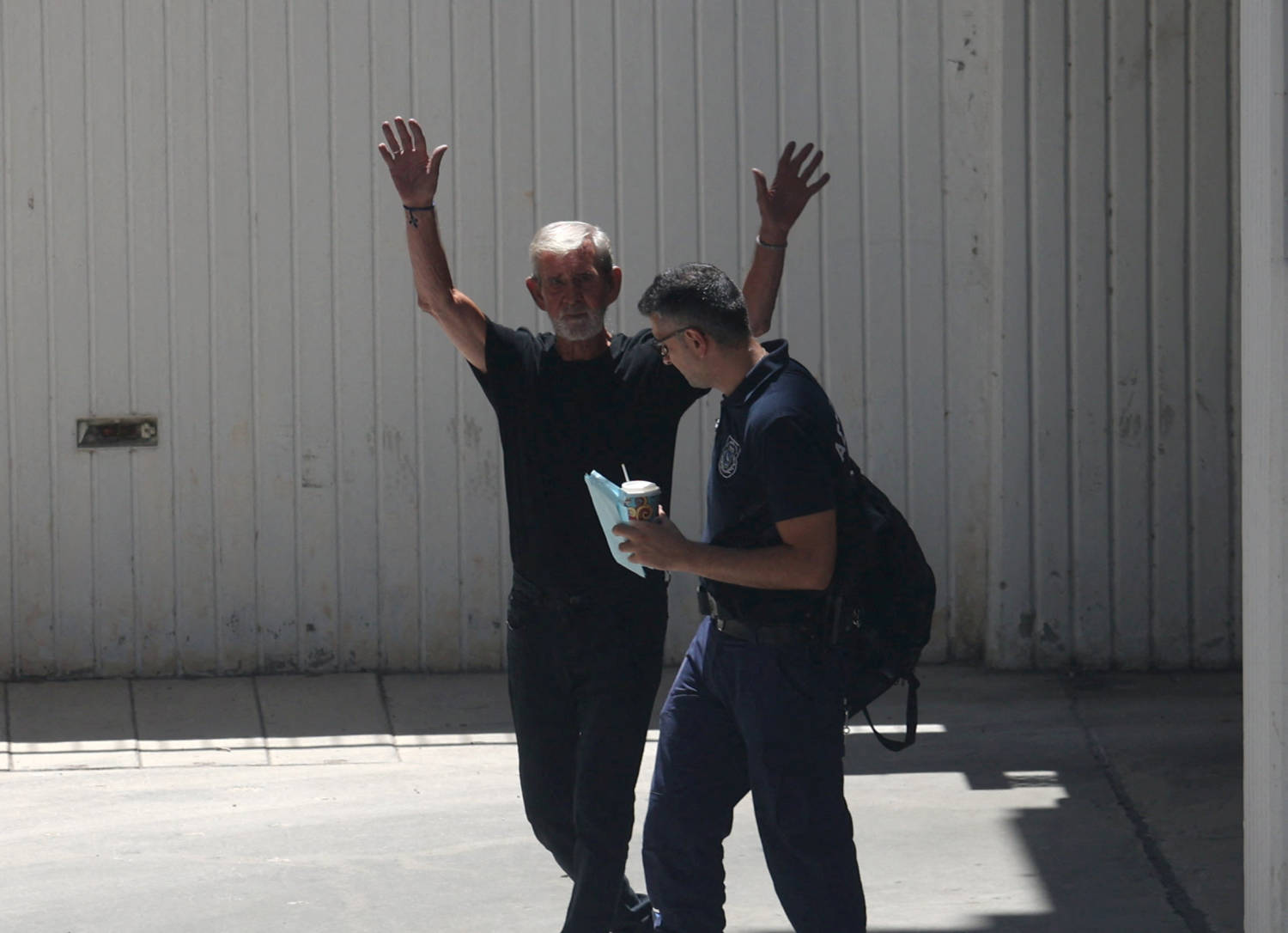 British Pensioner David Hunter Waves At Journalists While Being Escorted To A Police Van Outside A Courthouse In Paphos