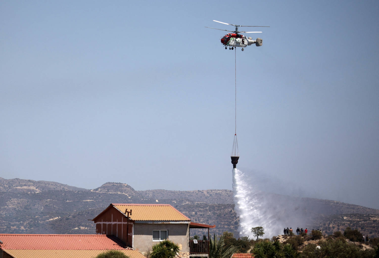 A Firefighting Helicopter Makes A Water Drop During A Wildfire Near The Village Of Alassa