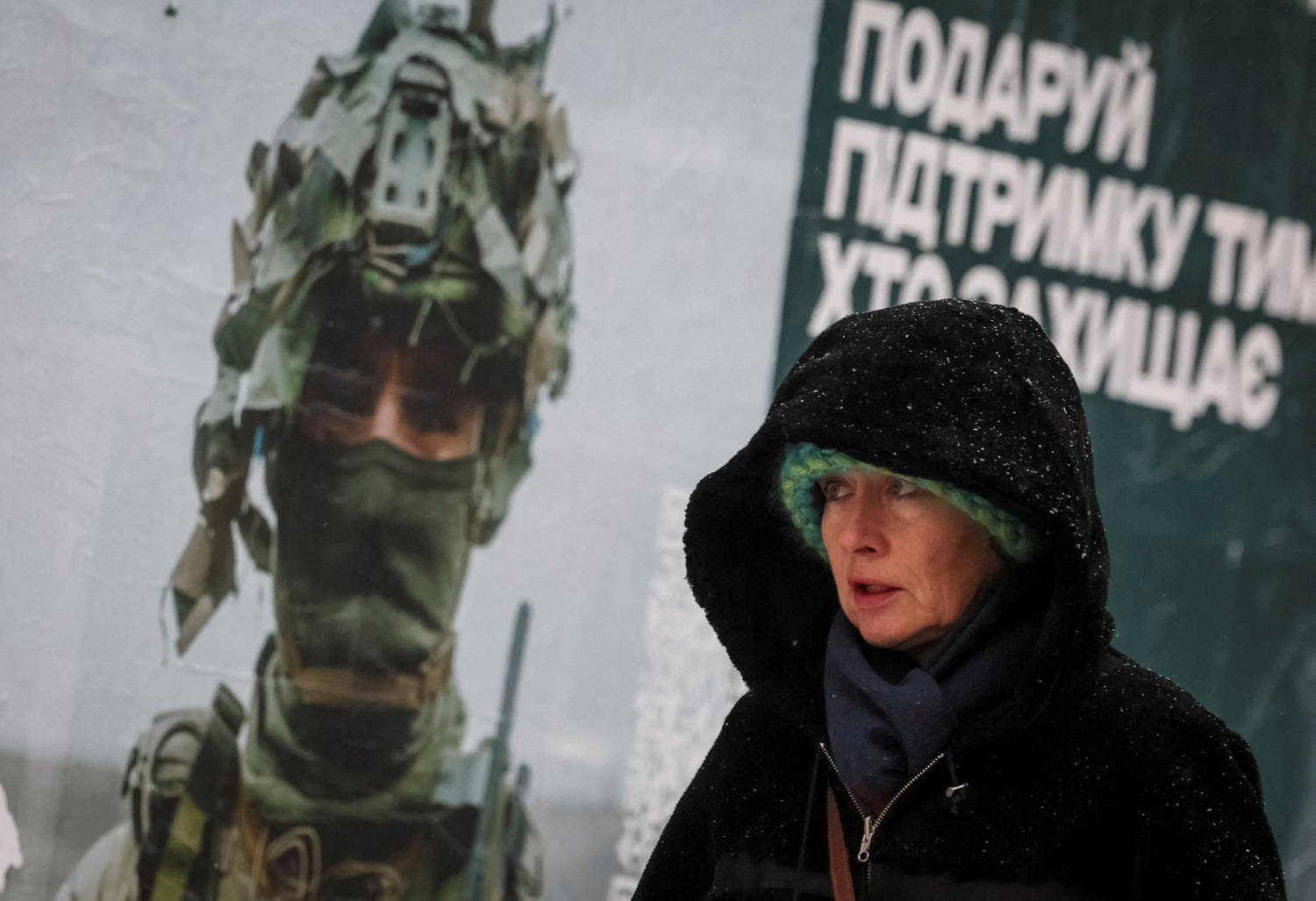 A Woman Walks Past An Advertising Poster Depicting A Ukrainian Serviceman During A Snowfall In Kyiv