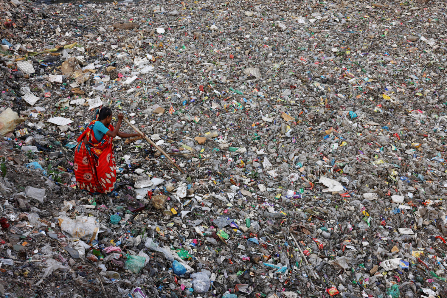 File Photo: A Woman Searches For Plastic Bottles To Collect From A Canal Full Of Waste In Dhaka
