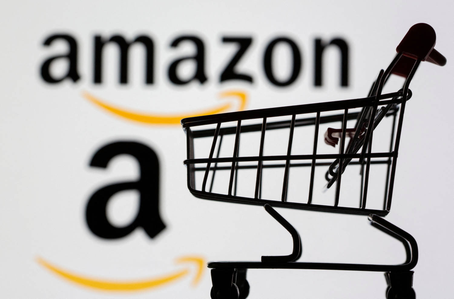 File Photo: Small Toy Shopping Cart Is Seen In Front Of Displayed Amazon Logo In This Illustration