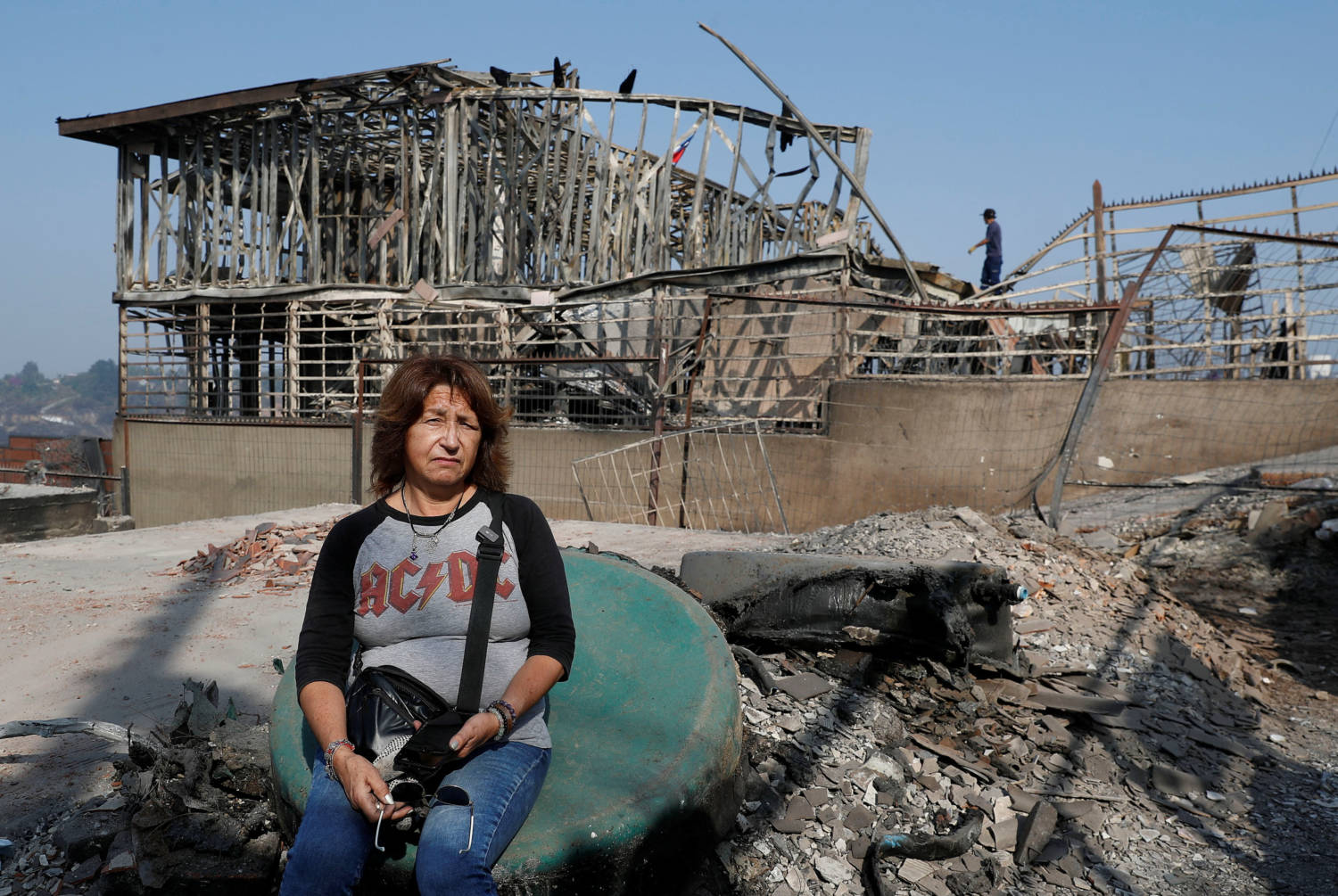 Ingrid Crespo Poses For A Picture Next To Remains Of Their Burned House, Following The Spread Of Wildfires In Vina Del Mar, Chile
