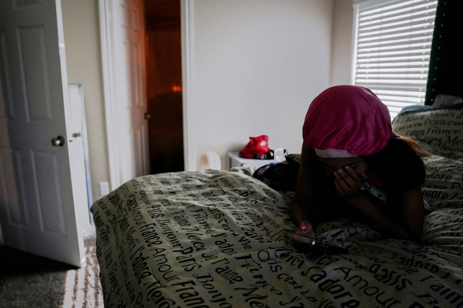 Adreiona Prater Checks Her Phone While Lying On The Bed Of Her Apartment In Dallas