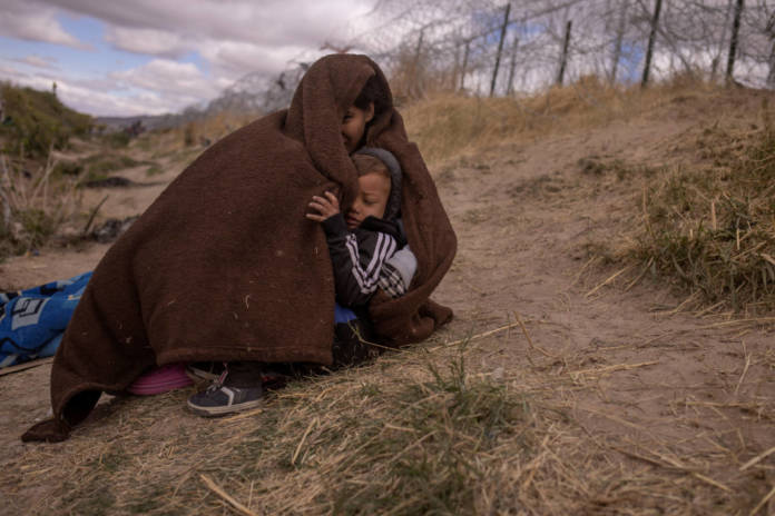 Migrant Mother Shelters Son From Cold Blustery Weather In El Paso, Texas