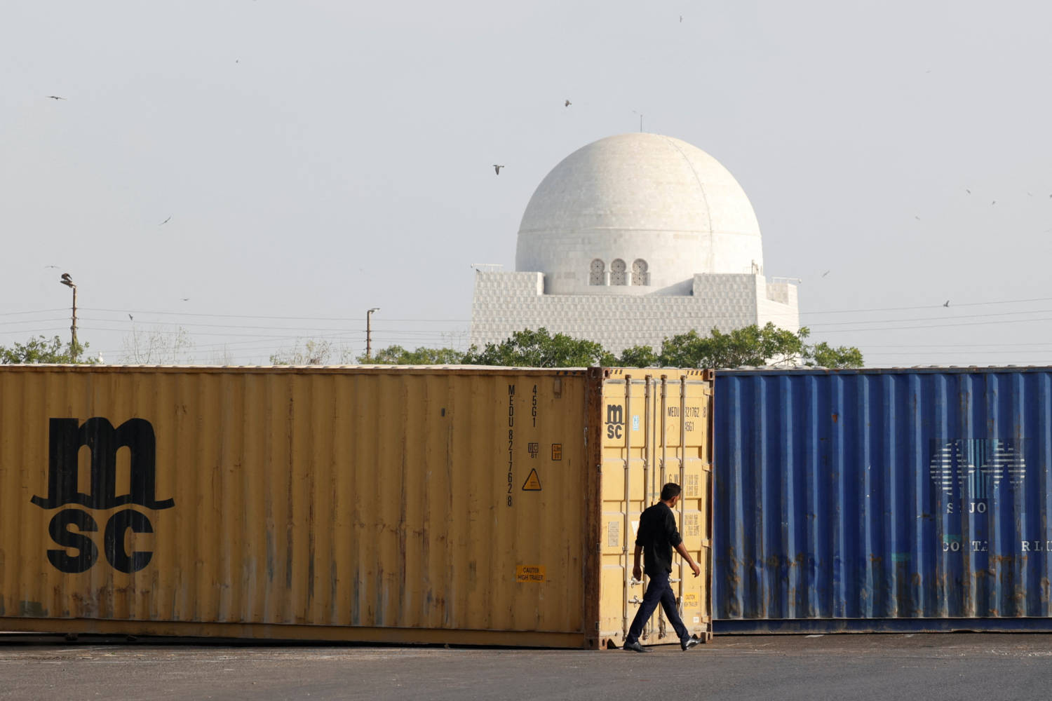 A Man Walks Past Shipping Containers, Used To Block The Area For Security Measures, Following The Visit Of The Iranian President Ebrahim Raisi, In Karachi