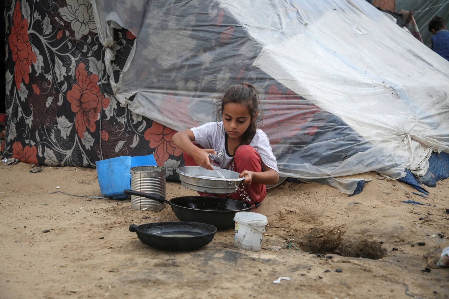 File Photo: A Girl Pours Water Next To A Tent, In Rafah