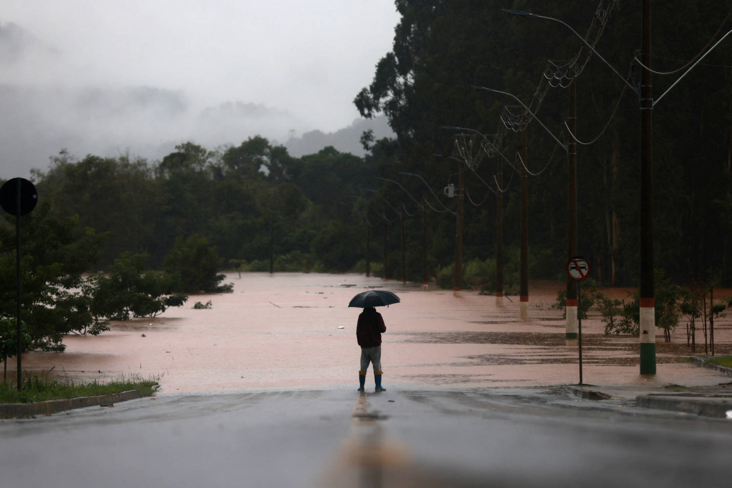 A Man Stands In Front Of Flooded Road Near The Taquari River During Heavy Rains In The City Of Encantado In Rio Grande Do Sul, Brazil